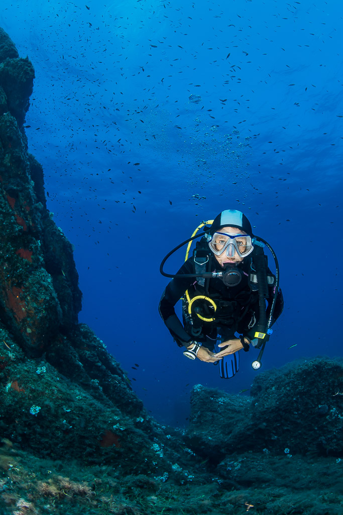 Woman diver hovering in a blue channel between rocks, Porto-Vecchio, Corsica, France
