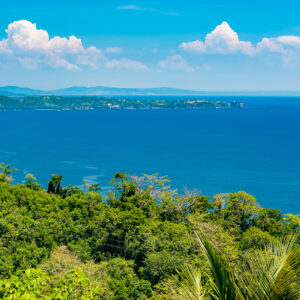 Wooded coastline and blue bay under white cumulus clouds, Puerto Galera, Mindoro, Philippines