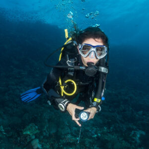 Woman diver with torch swimming toward camera above reef, Puerto Galera, Mindoro, Philippines