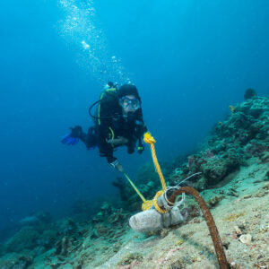 Woman diver holding a line above a sandy slope, vertical, Puerto Galera, Mindoro, Philippines