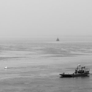 Mer brumeuse en noir et blanc, chaland de travail et tourelle balise au loin, Le Croisic, Bretagne, France