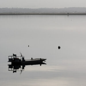 Eau calme monochrome, chaland de travail reflété entre les bouées de mouillage, Le Croisic, Bretagne, France