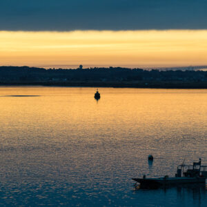 Ciel d’aube doré sur une baie calme, chaland de travail en silhouette, Le Croisic, Bretagne, France