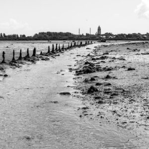 Chenal de marée en noir et blanc longeant une ligne de pieux usés, Le Croisic, Bretagne, France