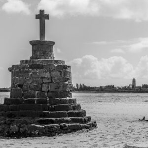 Black-and-white stone refuge cross on stepped base at low tide under clouds, Le Croisic, Brittany, France