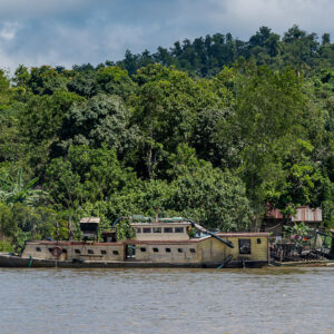 Abandoned wooden boat wreck beached on a forested riverbank, Maratua, Kalimantan (Borneo), Indonesia