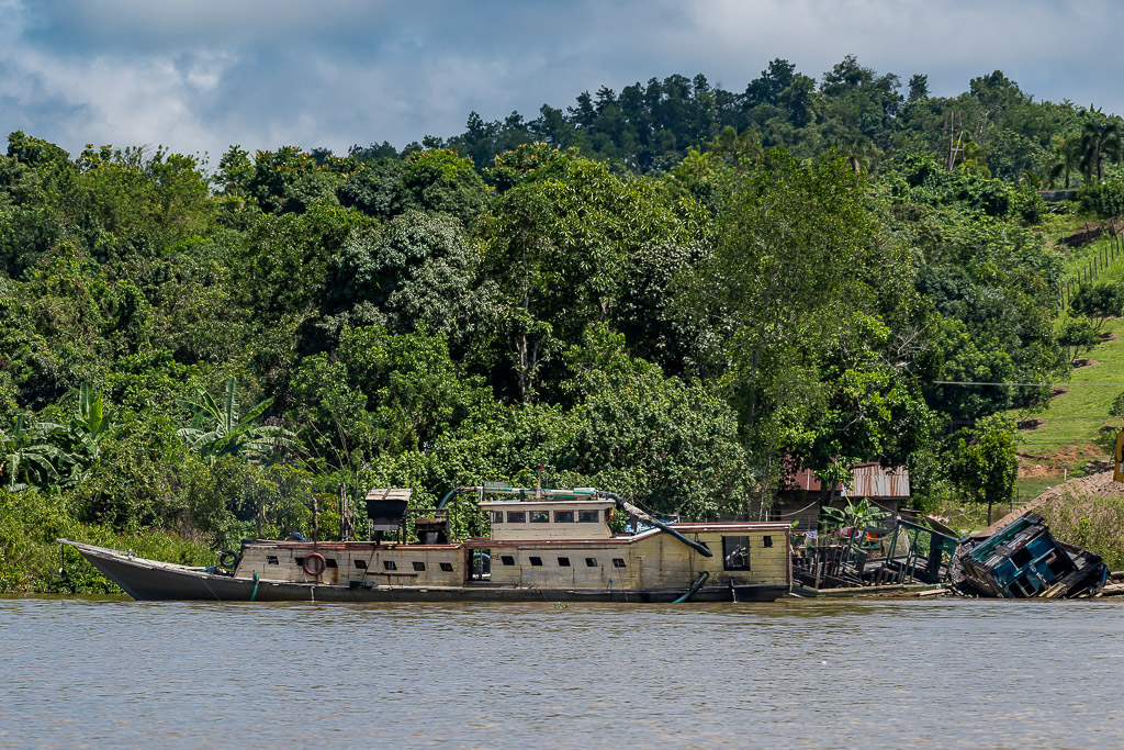 Abandoned wooden boat wreck beached on a forested riverbank, Maratua, Kalimantan (Borneo), Indonesia