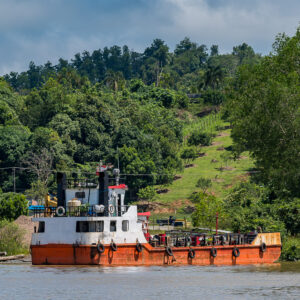 Bateau de servitude à coque orange amarré au pied d’une colline verdoyante, Maratua, Kalimantan (Bornéo), Indonésie