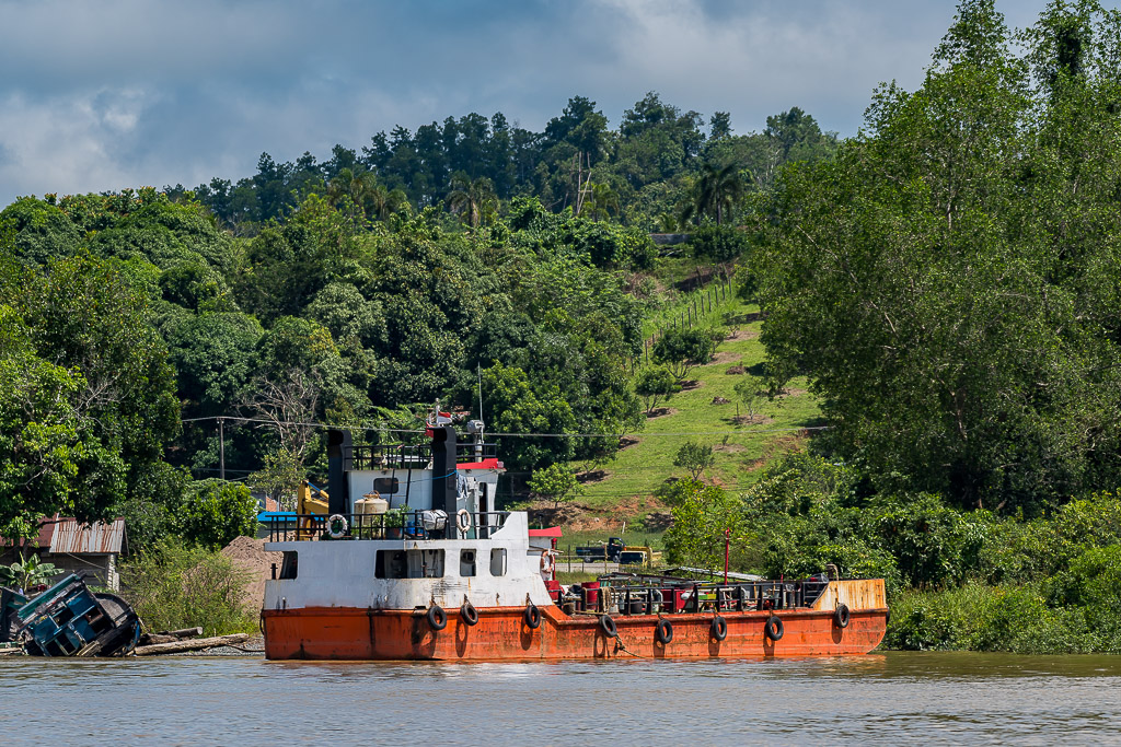 Bateau de servitude à coque orange amarré au pied d’une colline verdoyante, Maratua, Kalimantan (Bornéo), Indonésie