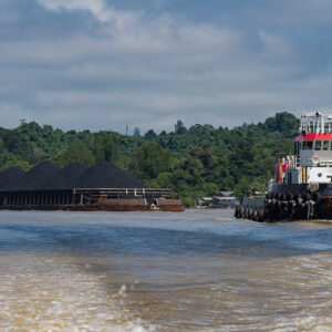 Tugboat towing a barge loaded with coal, boat wake in foreground, Maratua, Kalimantan (Borneo), Indonesia