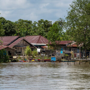 Stilt houses with brown roofs and a wooden jetty on the river, Maratua, Kalimantan (Borneo), Indonesia