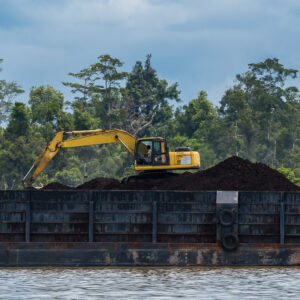 Yellow excavator working on a coal pile aboard a barge, Maratua, Kalimantan (Borneo), Indonesia