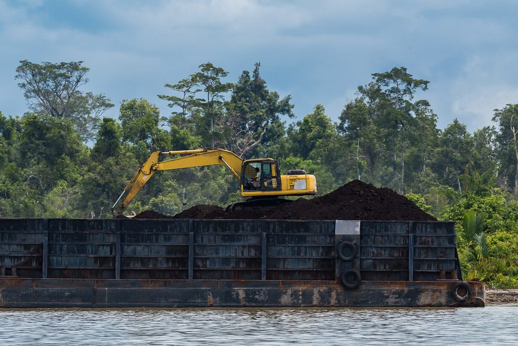 Yellow excavator working on a coal pile aboard a barge, Maratua, Kalimantan (Borneo), Indonesia