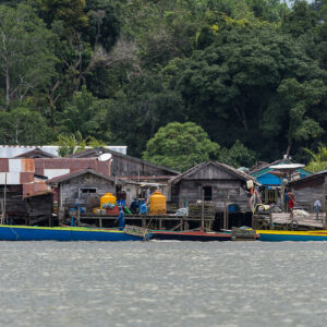Stilt houses with blue boats and yellow jerrycans on the waterfront, Maratua, Kalimantan (Borneo), Indonesia