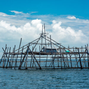 Bagang fishing platform with central mast against bright cumulus clouds, Maratua, Kalimantan (Borneo), Indonesia