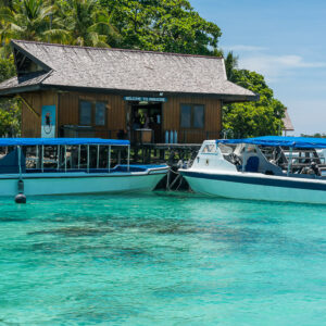 Two dive boats with blue canopies moored at a wooden dive centre, Maratua, Kalimantan (Borneo), Indonesia