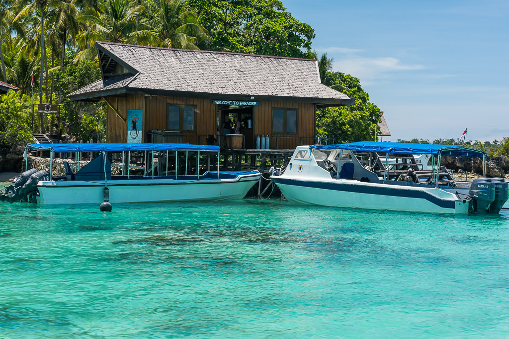 Deux bateaux de plongée à taud bleu amarrés devant un centre de plongée en bois, Maratua, Kalimantan (Bornéo), Indonésie