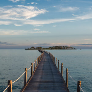 Wooden jetty leading to a distant island at dusk, vertical, Maratua, Kalimantan (Borneo), Indonesia