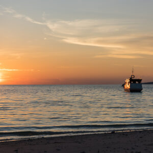 Sunset on the sea with an anchored boat seen from the beach, Maratua, Kalimantan (Borneo), Indonesia