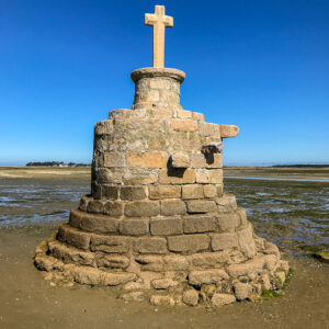 Stone refuge cross on round masonry base against deep blue sky, Le Croisic, Brittany, France