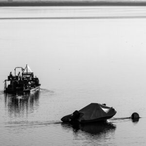 Black-and-white vertical work barge and covered boat at moorings on still water, Le Croisic, Brittany, France