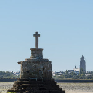 Vertical stone refuge cross on stepped base with distant church tower, Le Croisic, Brittany, France