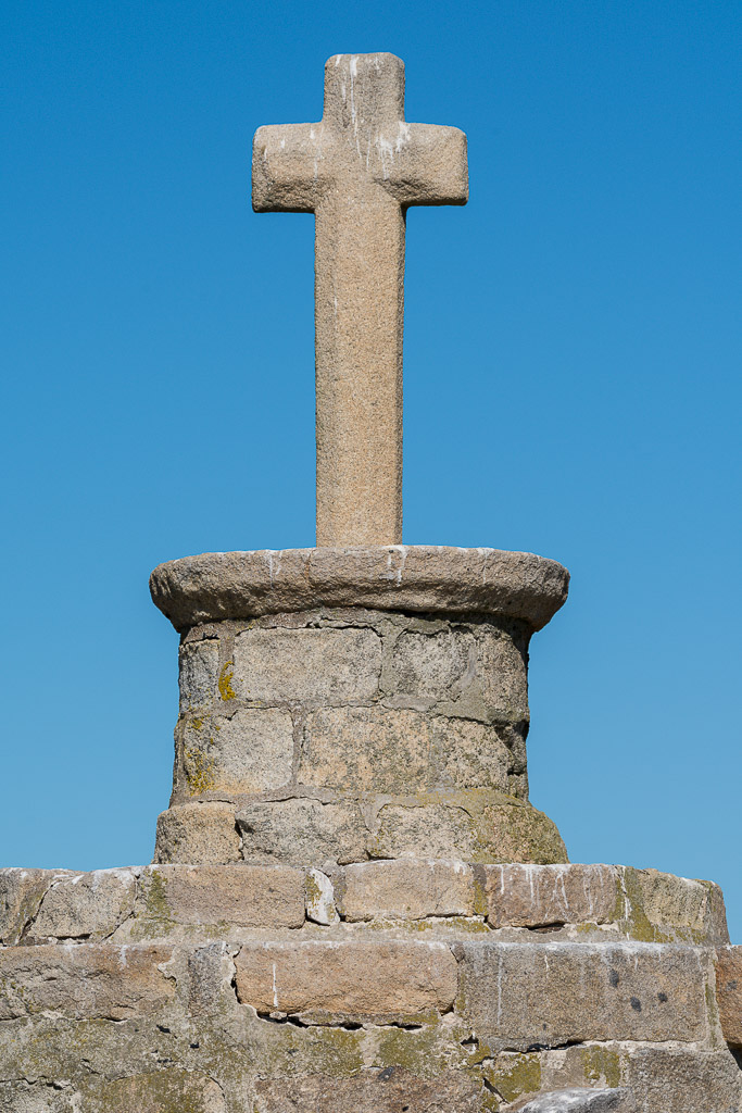 Close-up of granite cross atop round stone column against blue sky, Le Croisic, Brittany, France