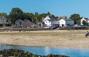 Panoramic beach with families gathering shellfish below seaside village houses, Le Croisic, Brittany, France