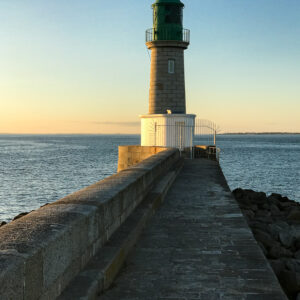 Phare à lanterne verte au bout d’une jetée de pierre au crépuscule, Le Croisic, Bretagne, France