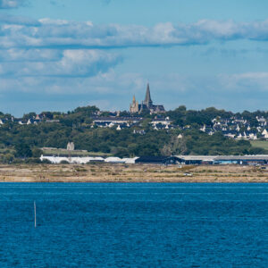 Church spires above coastal village across deep blue bay with two stakes, Le Croisic, Brittany, France