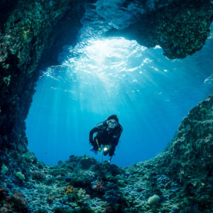 Woman diver approaching the camera through a cave entrance, Misool, Raja Ampat, Indonesia