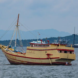 Cream and red wooden cargo boat at anchor in a bay, Misool, Raja Ampat, Indonesia