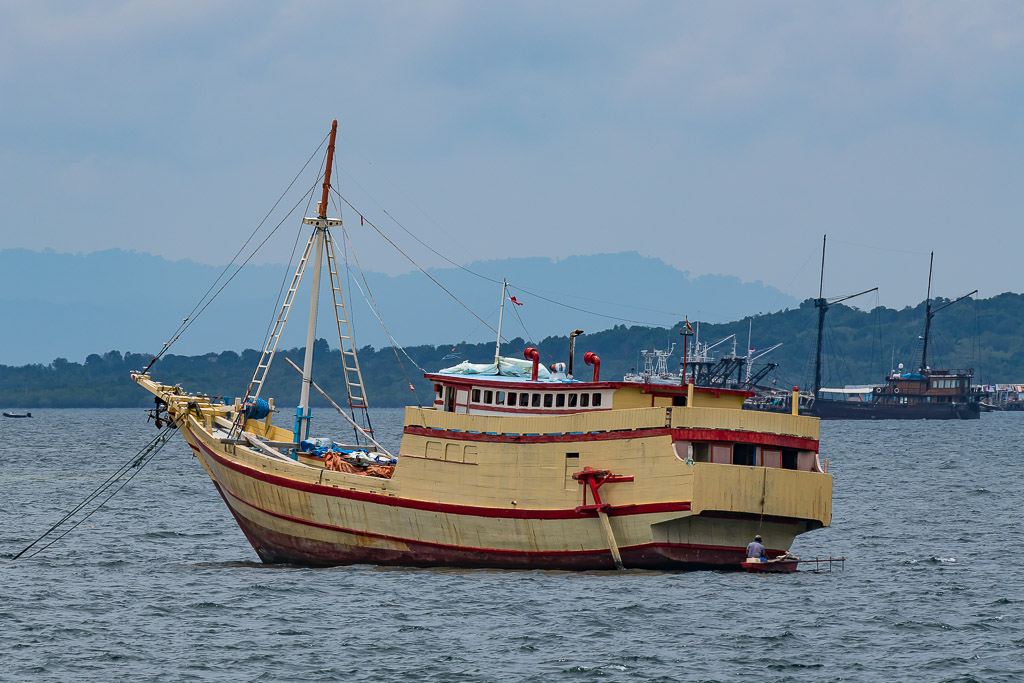 Cream and red wooden cargo boat at anchor in a bay, Misool, Raja Ampat, Indonesia