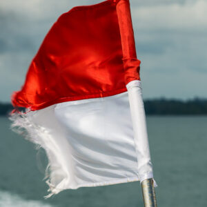Drapeau indonésien effiloché flottant sur un bateau, vertical, Misool, Raja Ampat, Indonésie