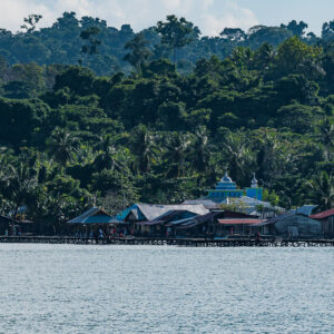 Village sur pilotis avec mosquée bleue au pied de collines couvertes de jungle, Misool, Raja Ampat, Indonésie