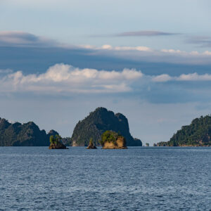 Chain of small karst islets on the horizon under soft clouds, Misool, Raja Ampat, Indonesia