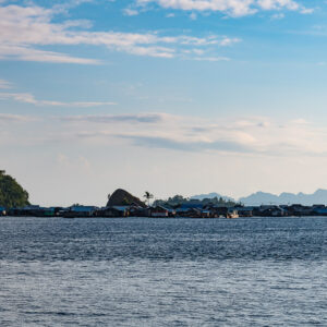 Distant stilt village and mosque on the horizon, karst peaks beyond, Misool, Raja Ampat, Indonesia