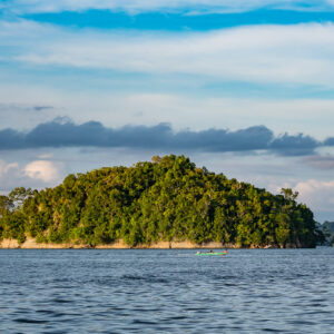 Rounded wooded island under layered clouds and blue sky, Misool, Raja Ampat, Indonesia
