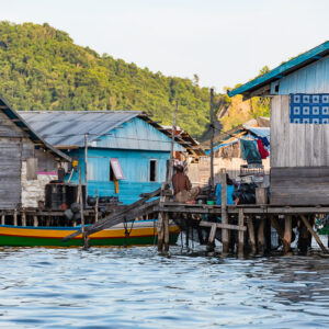 Wooden stilt houses with a yellow and green boat moored alongside, Misool, Raja Ampat, Indonesia