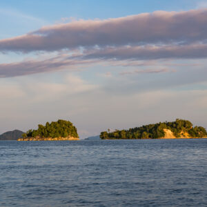 Two wooded islets at dusk under pink and grey clouds, Misool, Raja Ampat, Indonesia