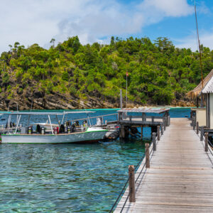 Wooden jetty with hut on the right and dive boats moored, offset view, Misool, Raja Ampat, Indonesia