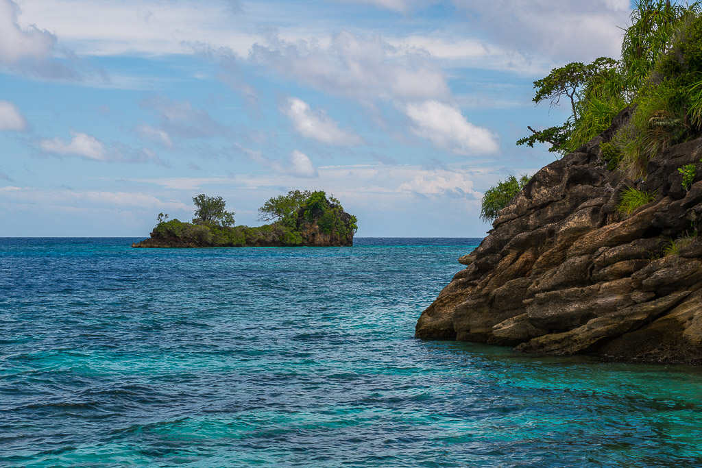 Rocky headland on the right with a small islet across turquoise water, Misool, Raja Ampat, Indonesia