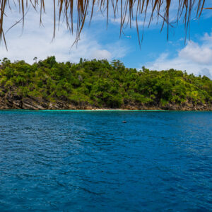 Wooded island framed by the fringe of a thatched roof, Misool, Raja Ampat, Indonesia