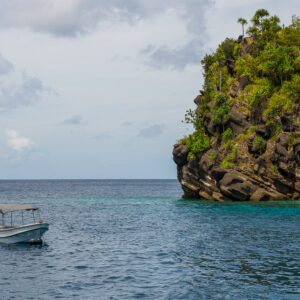 Small boat near a rocky jungle-topped islet, Misool, Raja Ampat, Indonesia