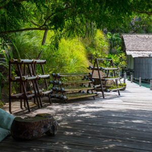 Shaded boardwalk with wooden planter racks and cushions near bungalows, Misool, Raja Ampat, Indonesia