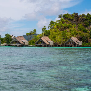 Vue frontale d’une rangée de bungalows le long de la rive d’une île boisée, Misool, Raja Ampat, Indonésie