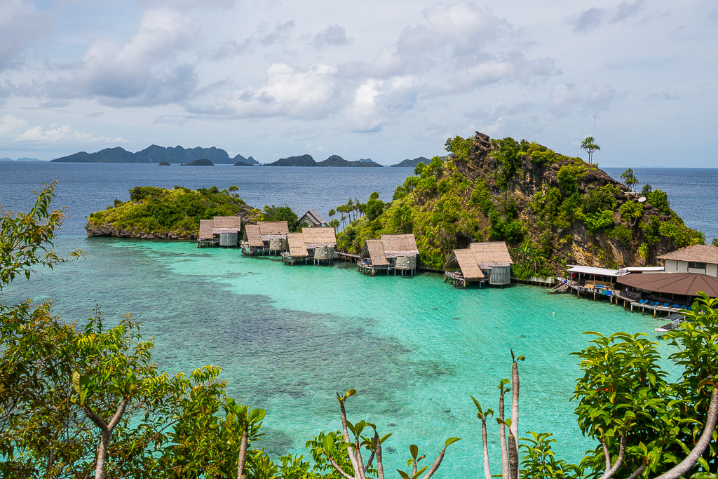 Vue en surplomb du lagon et des bungalows sur pilotis avec des îles au loin, Misool, Raja Ampat, Indonésie