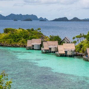 Vue en surplomb de bungalows sur une pointe du lagon, encadrée de feuillages, Misool, Raja Ampat, Indonésie
