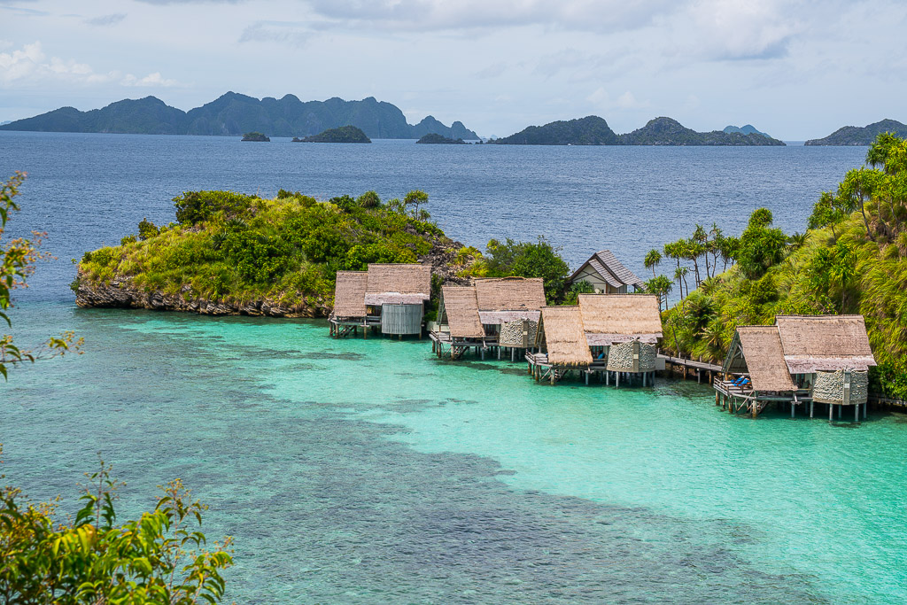 Elevated view of bungalows on a lagoon point framed by foliage, Misool, Raja Ampat, Indonesia
