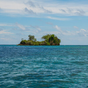 Small rocky wooded islet alone on a deep blue sea, Misool, Raja Ampat, Indonesia